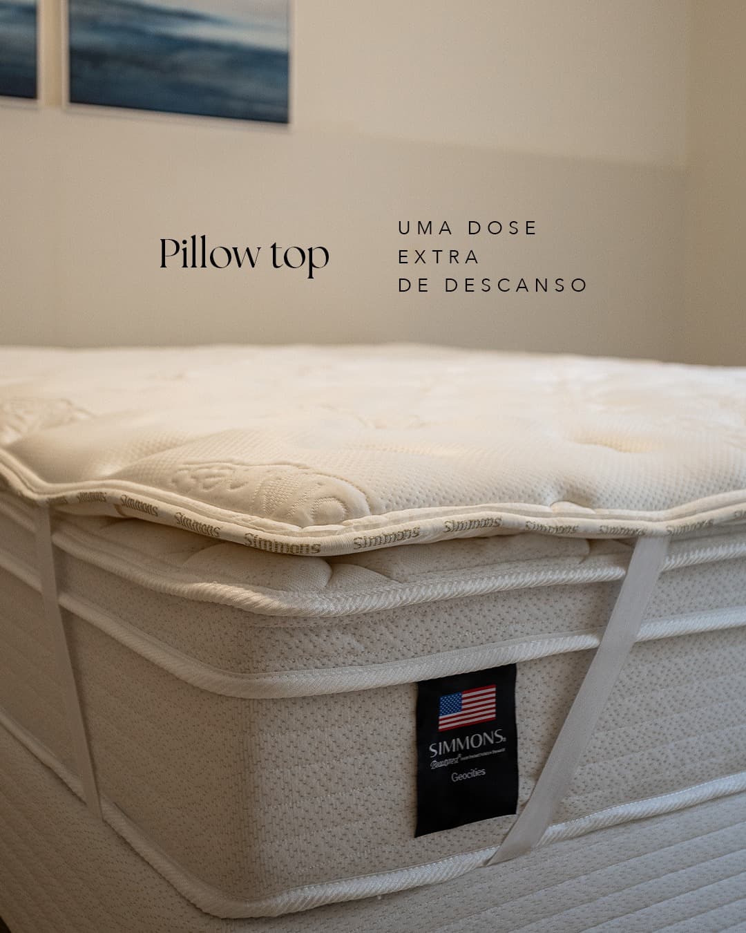 Pillow top do colchão Simmons New Geocities visto de perto, com a etiqueta Beautyrest à mostra e a legenda “Pillow top — uma dose extra de descanso”